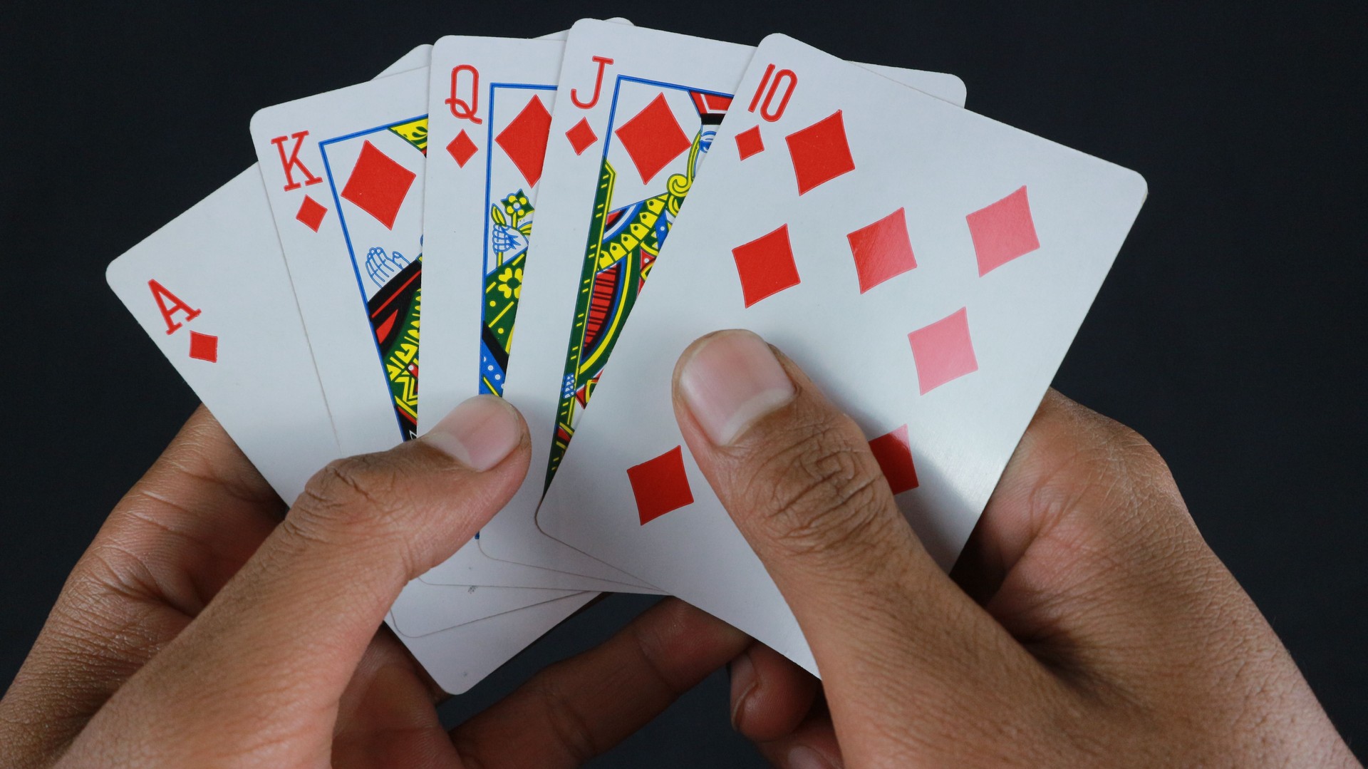 Hand with poker cards isolated on dark background Hand with poker cards isolated on dark background